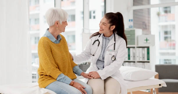 A female doctor converses with an elderly woman in a medical office, discussing health concerns